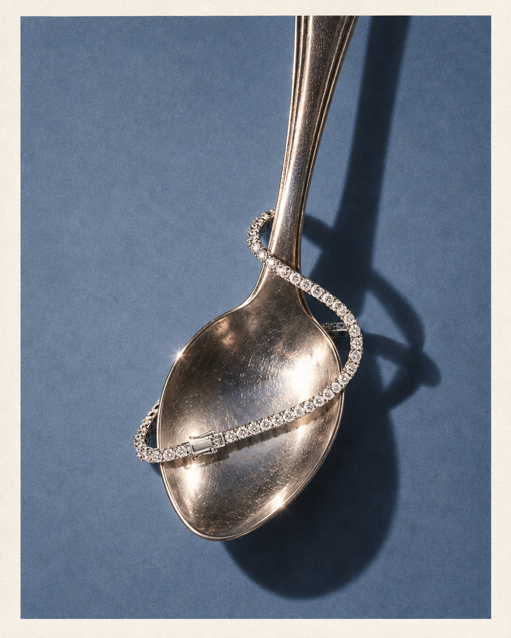 Diamond tennis bracelet styled around a spoon on a steel blue background
